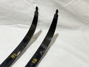 Two black recurve bow limbs placed on a white fabric background.