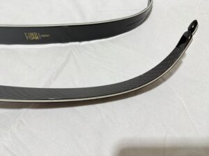 Two traditional archery bows lying on a white surface.