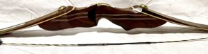 A traditional wooden recurve bow with an arrow placed below it.