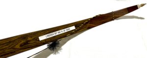 A chimney sweep brush with a wooden handle and label.