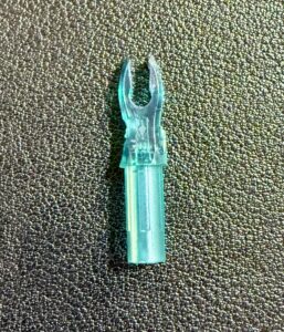 A transparent blue plastic connector piece on a textured black surface.