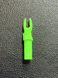 Bright green plastic tool with a forked end on a textured black surface.