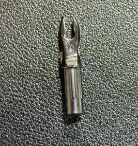 Close-up of a black slotted screwdriver bit on a textured surface.