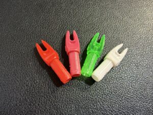Four colorful plastic archery nocks on a black surface.