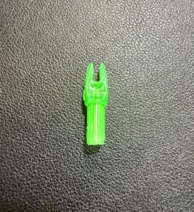 A small green plastic piece on a textured black surface.