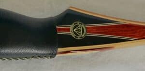 Close-up of a black and gold object with a circular emblem and red stripes.