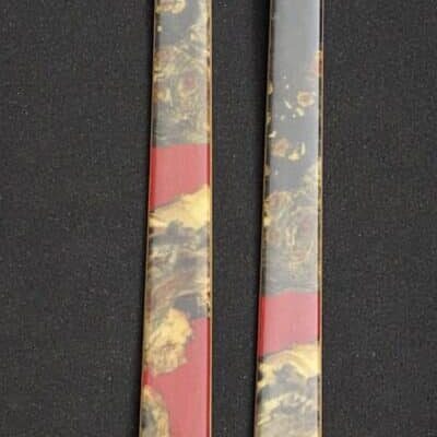Two ornate chopsticks with red and gold decorative patterns.