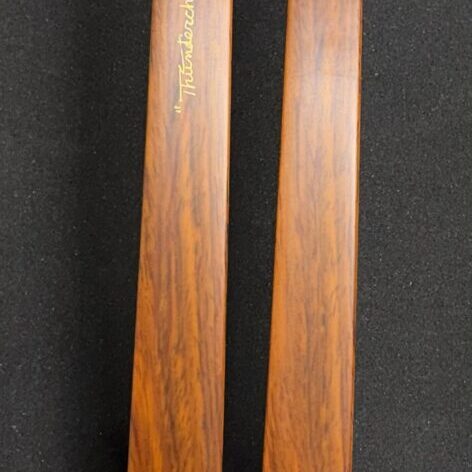 Close-up of two wooden ski tips with a smooth finish on a black background.