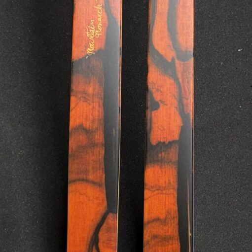 Close-up of two wooden objects with distinct reddish and black grain patterns.